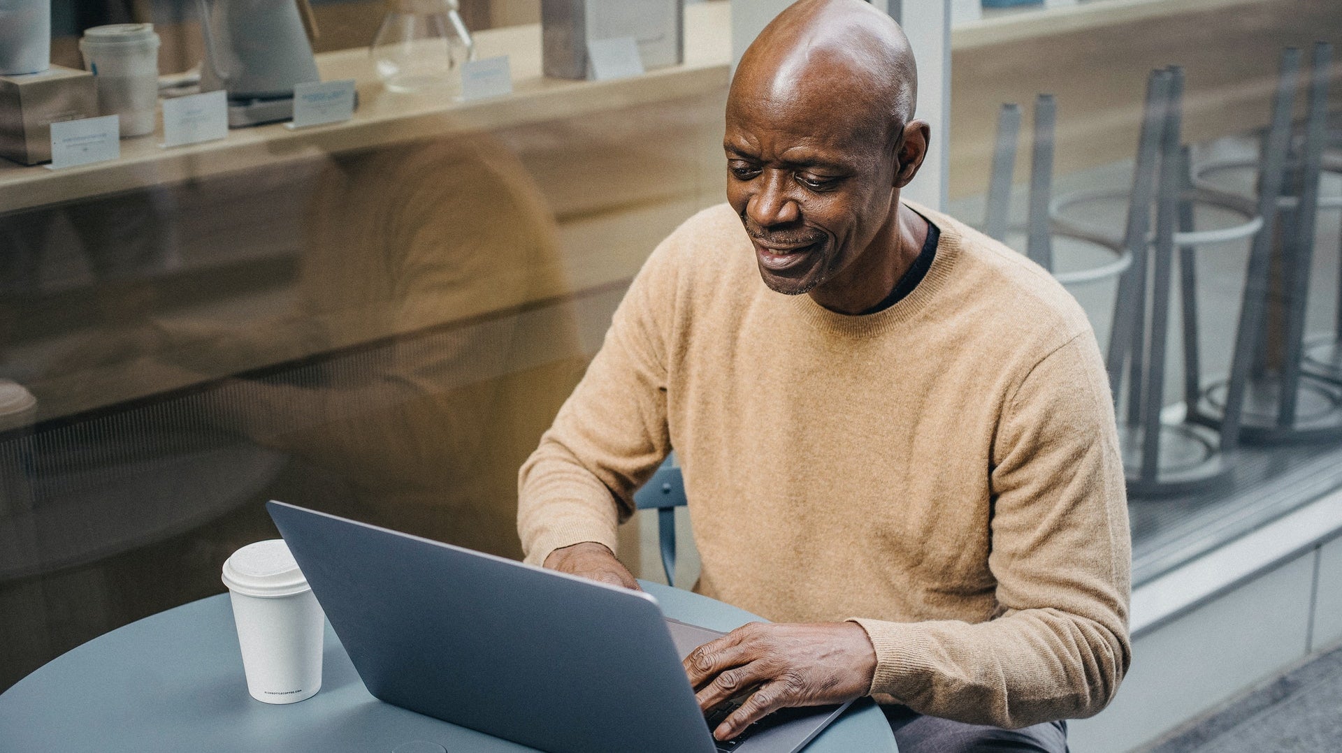 Mann mit Glatze sitzt am Laptop