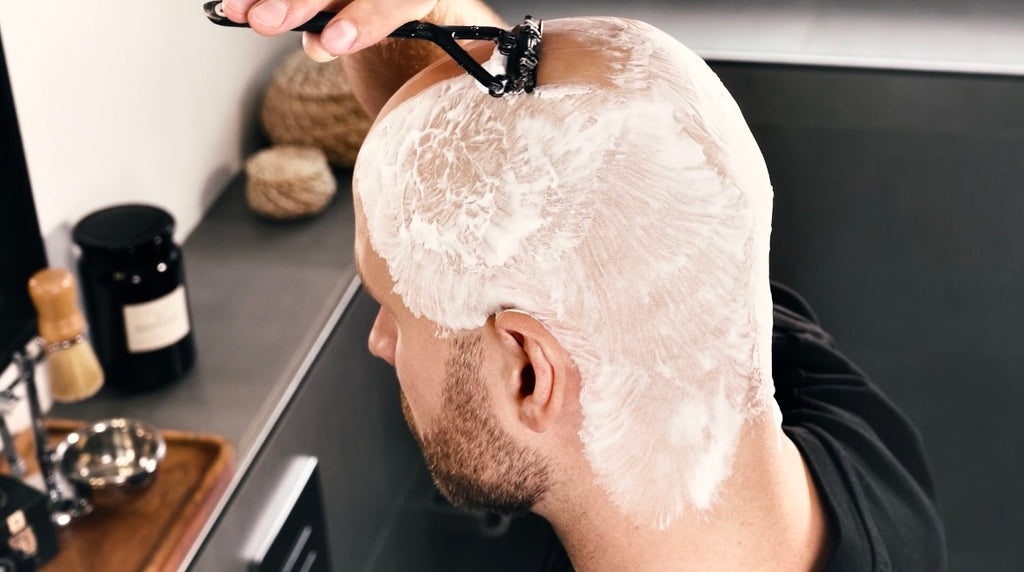 Mann beim Glatze rasieren