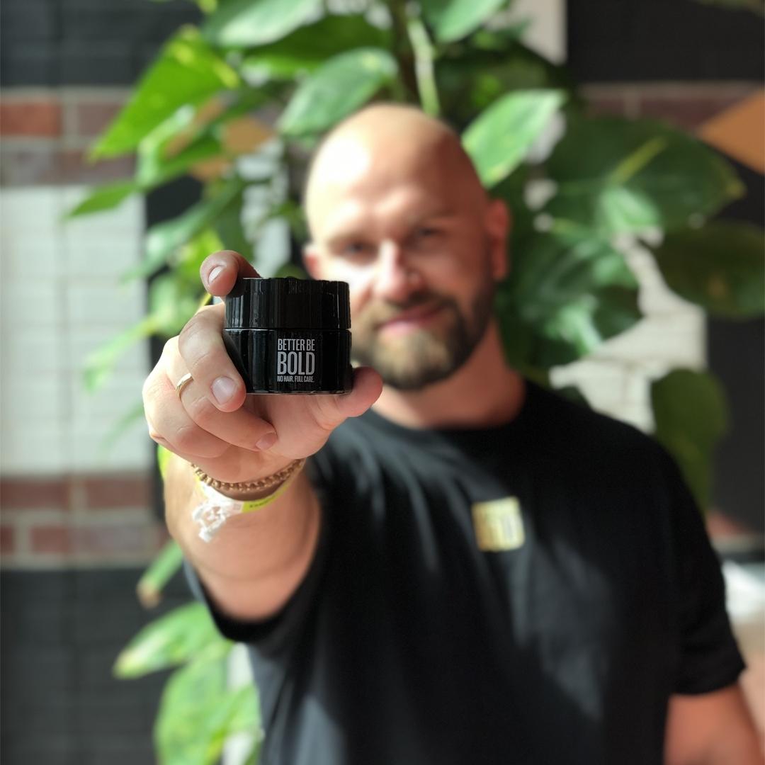 Dennis Baltzer, Mitgründer von Better Be Bold mit Glatzencreme in der Hand
